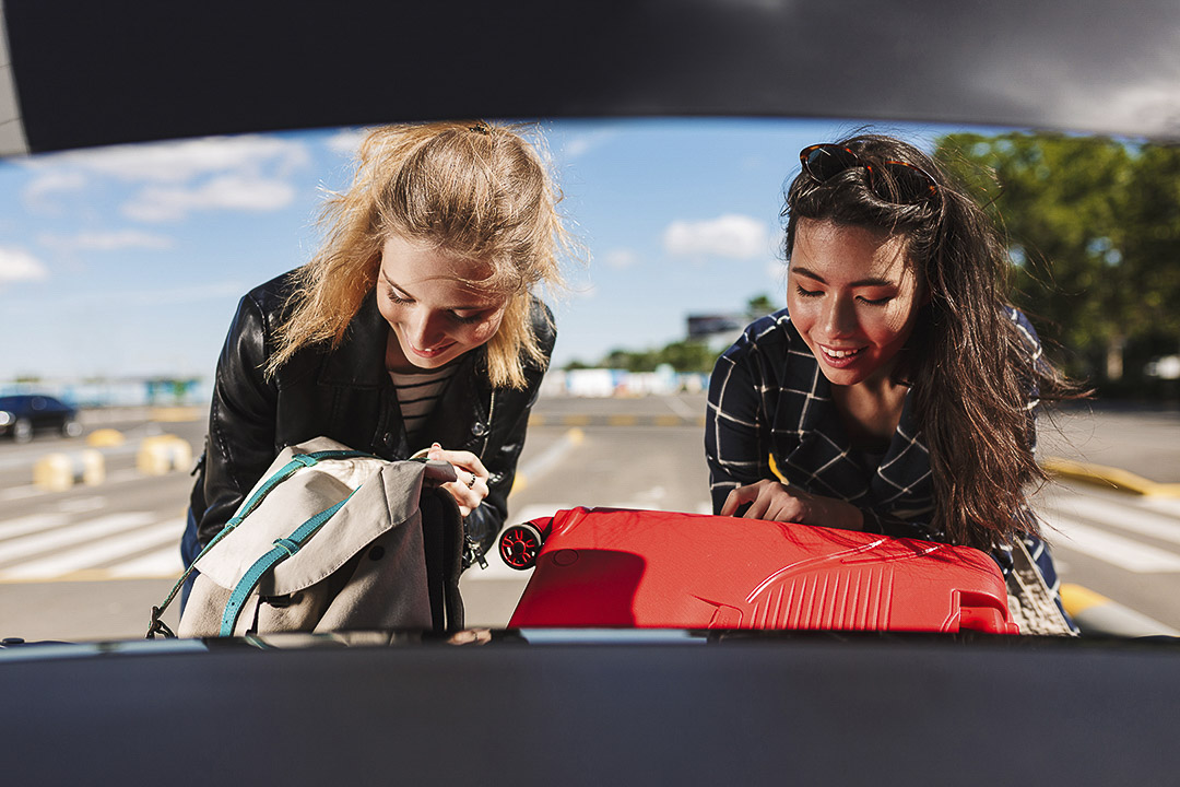 Two friends packing the car for a road trip