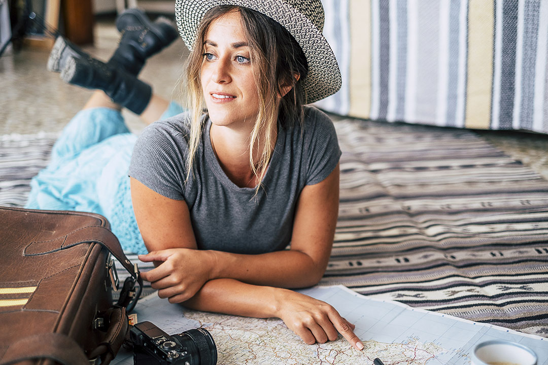 A girl planning her trip on a map next to her luggage