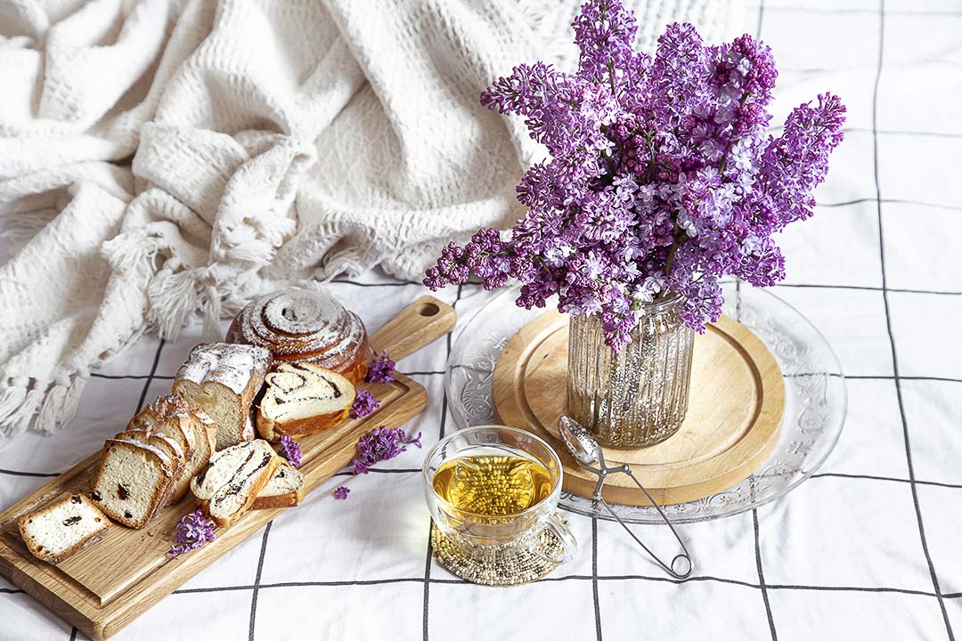 A breakfast in bed with a bouquet of lilacs