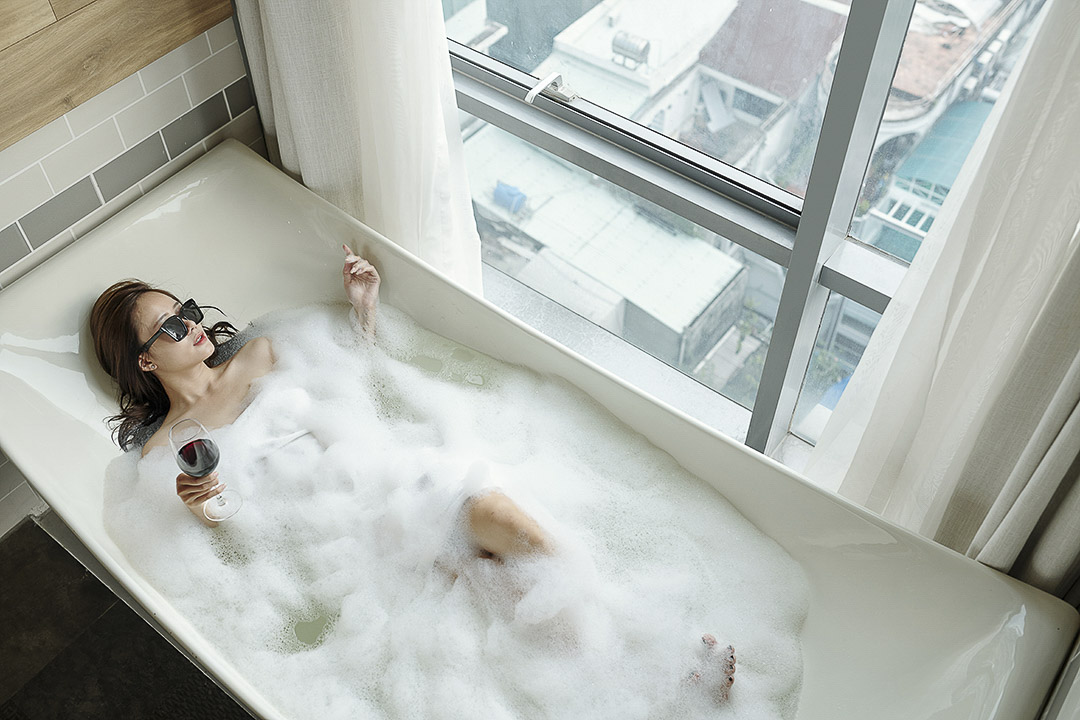 a women relaxing in a bubble bath with a glass of wine